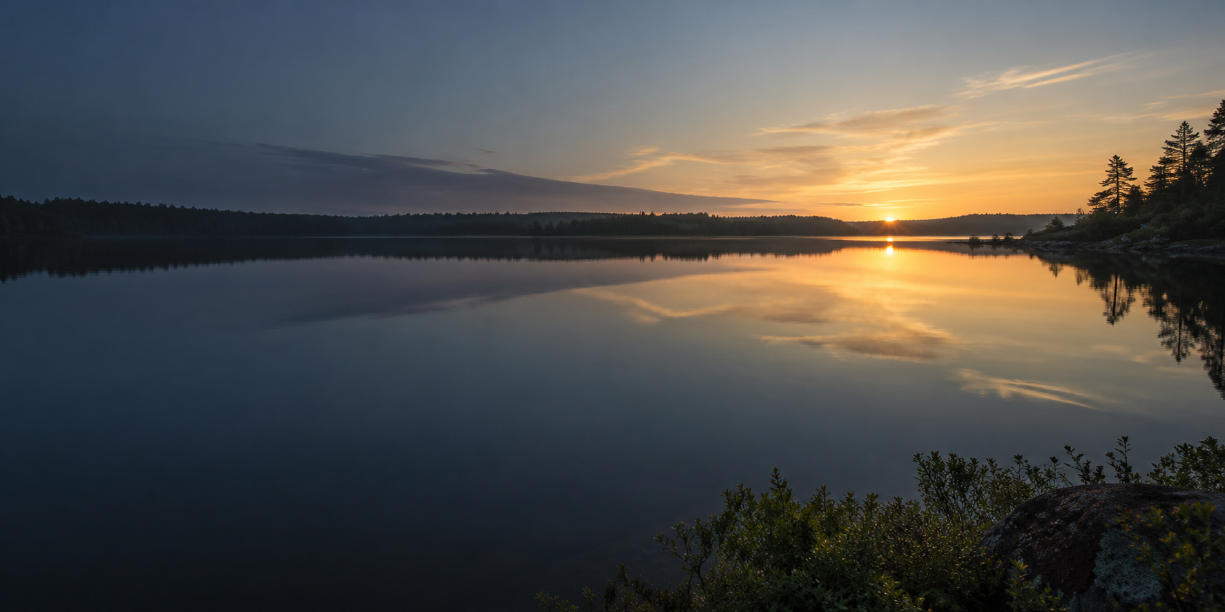Still lake reflecting the first light of dawn